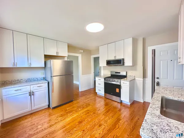 a kitchen with granite countertop a refrigerator stove top oven and sink