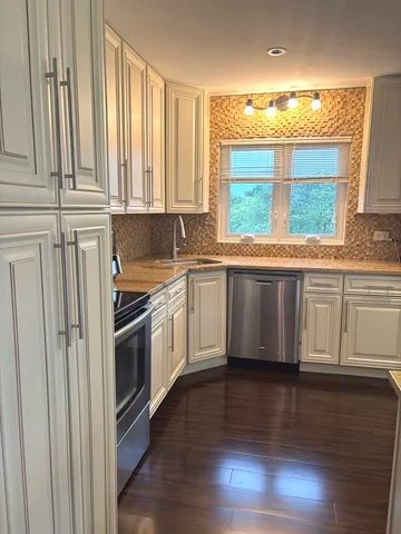 a kitchen with granite countertop white cabinets and wooden floor