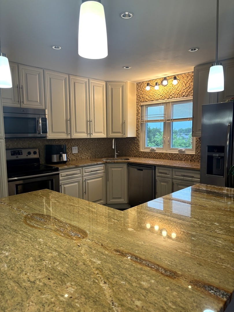 9332 Landings Lane, Unit 504 Des Plaines, IL 60016 - Photo 9 of 18 a large kitchen with stainless steel appliances a large counter top a stove a sink dishwasher and a flat tv screen