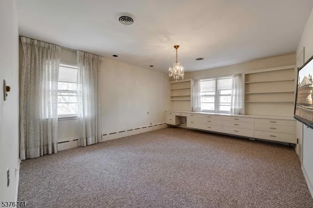 an empty room with chandelier fan and windows