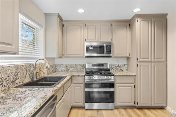 a kitchen with granite countertop a sink stainless steel appliances and cabinets