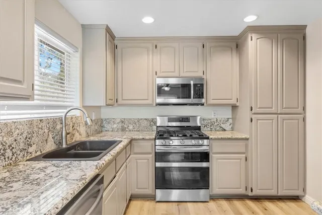 a kitchen with granite countertop a sink stainless steel appliances and cabinets