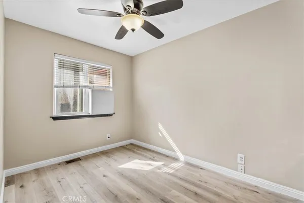 an empty room with a window and ceiling fan