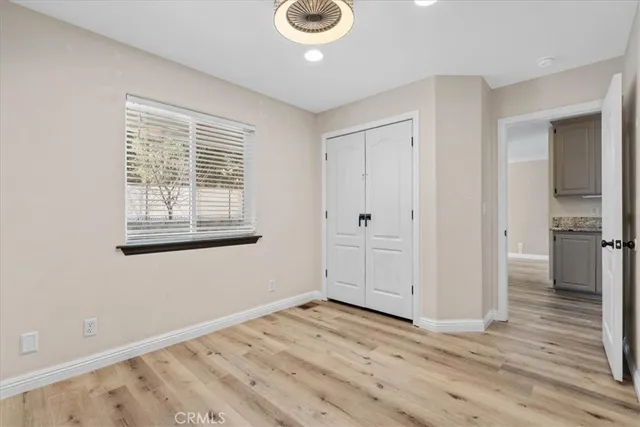 a view of empty room with wooden floor and fan
