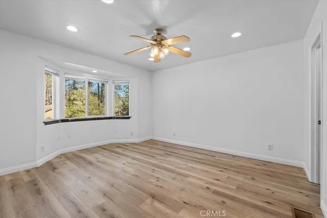 a view of an empty room with window and wooden floor