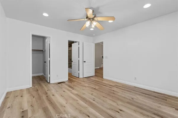an empty room with wooden floor and a ceiling fan