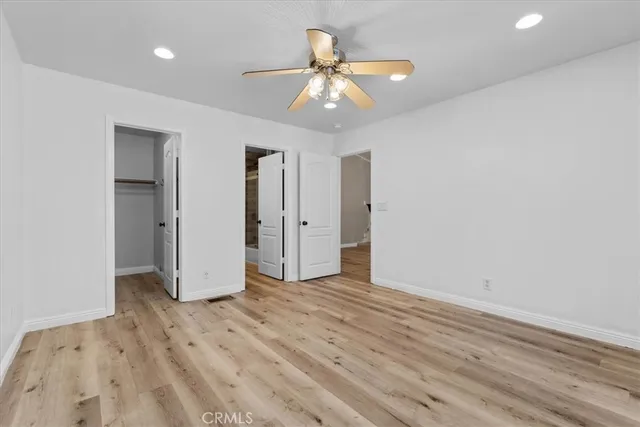 an empty room with wooden floor and a ceiling fan