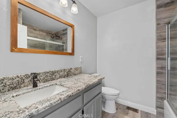 a bathroom with a granite countertop sink a toilet and a mirror