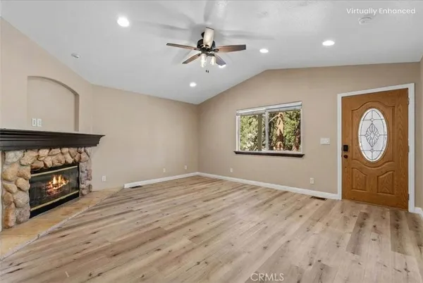 an empty room with wooden floor a ceiling fan and a fireplace
