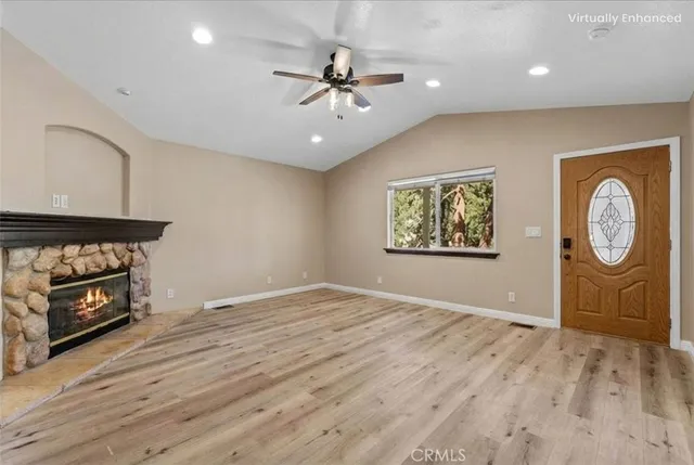 an empty room with wooden floor a ceiling fan and a fireplace
