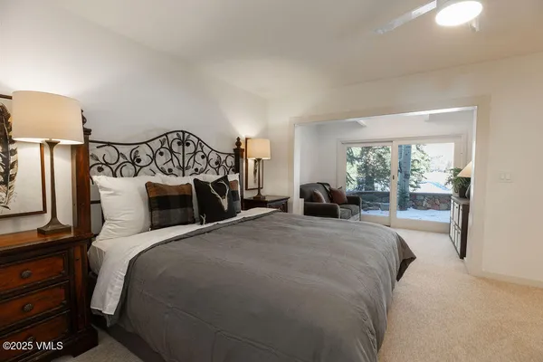 a bedroom with a large bed and a lamp on dresser