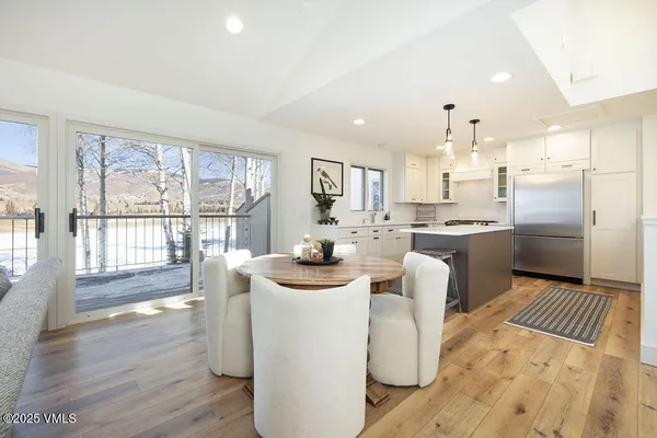 a kitchen with stainless steel appliances kitchen island granite countertop a refrigerator a sink a stove and white cabinets with wooden floor