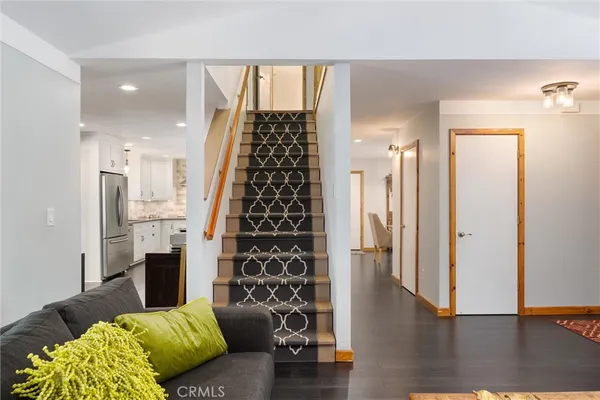 a kitchen with stainless steel appliances granite countertop a refrigerator a sink dishwasher a stove and white cabinets with wooden floor
