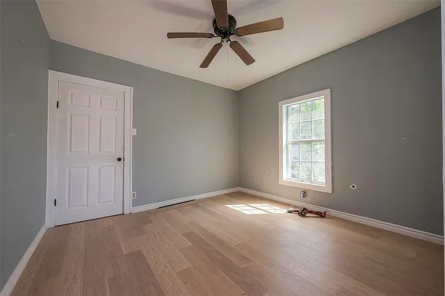 an empty room with windows and fan
