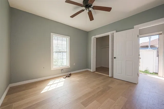 a view of empty room with wooden floor and fan