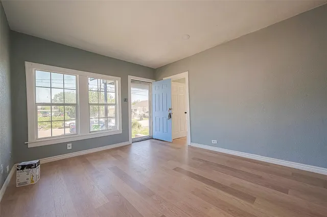 an empty room with wooden floor and windows