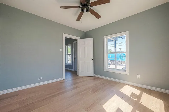 a view of an empty room with a window and wooden floor