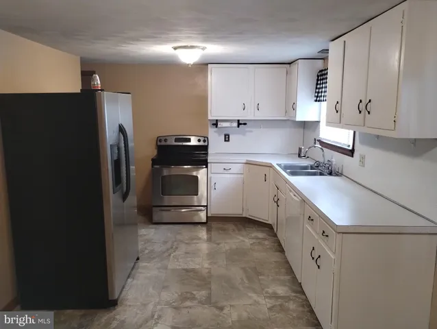 a kitchen with a sink a refrigerator and cabinets