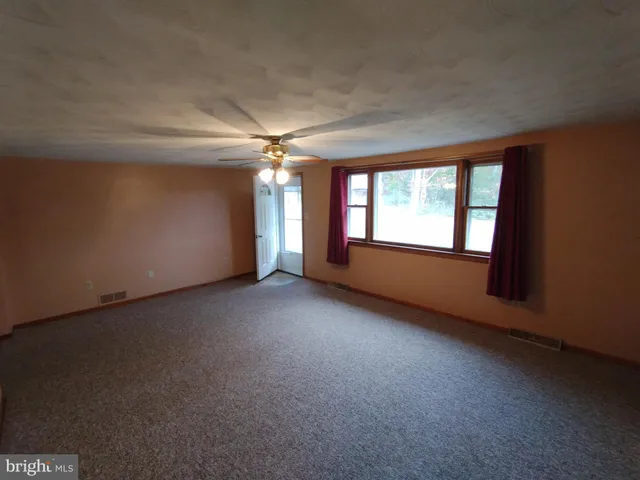 an empty room with windows and chandelier fan