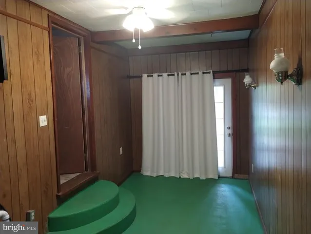 a view of a elevator and an empty room with wooden floor