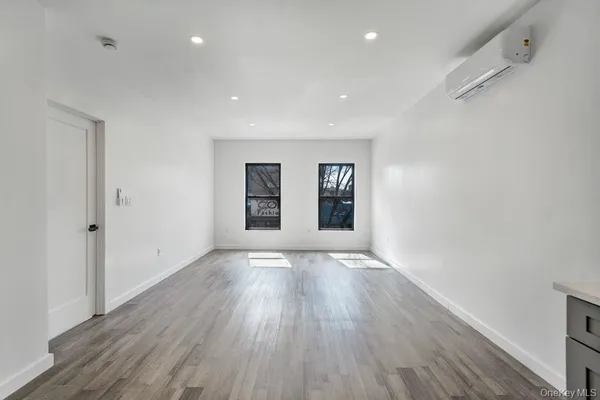 a view of an empty room with wooden floor and window