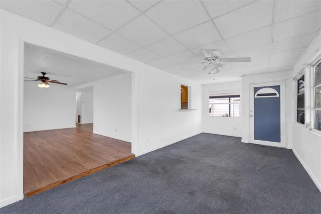 an empty room with chandelier fan and windows