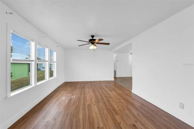 a view of empty room with wooden floor and fan