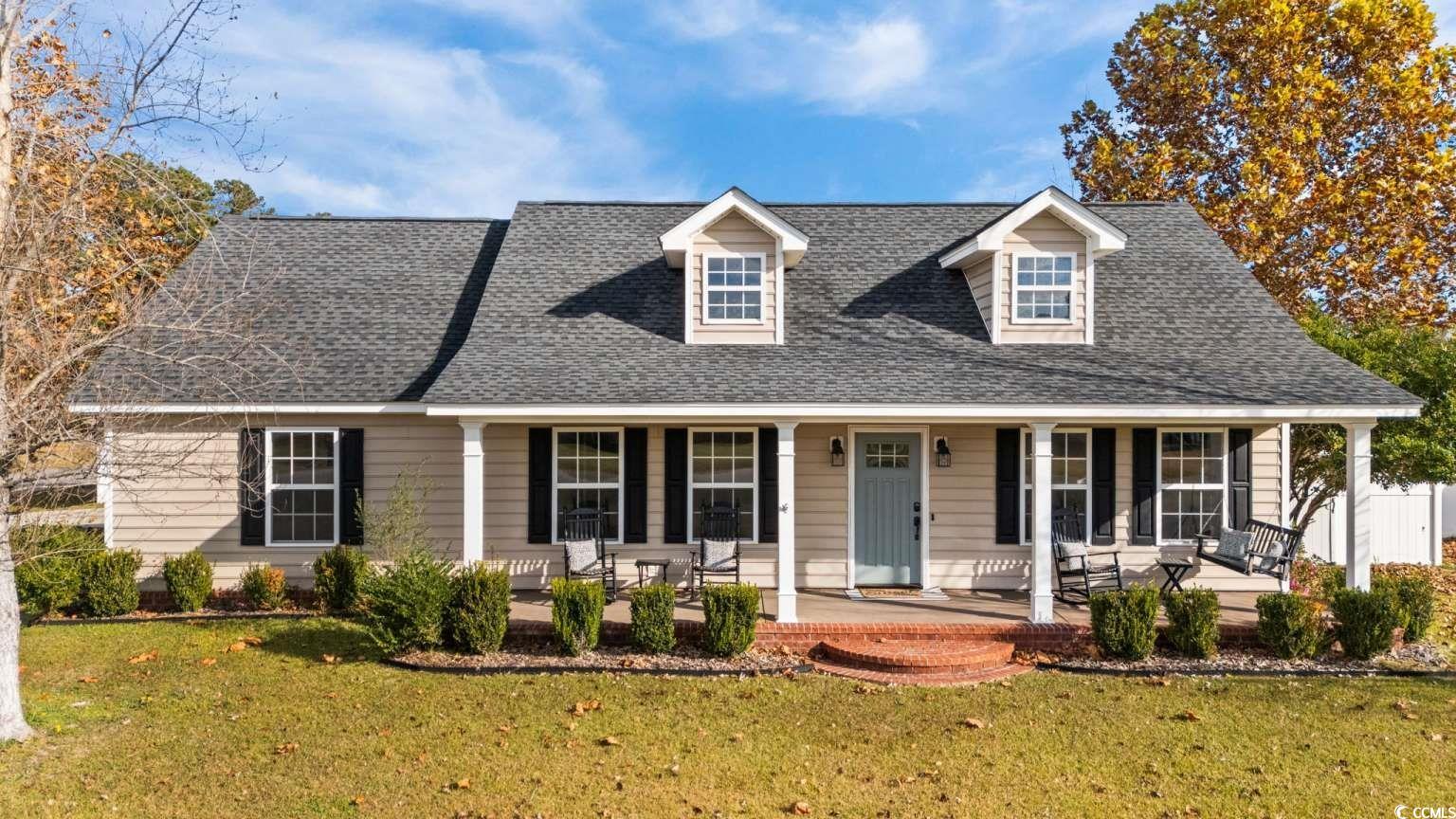 Cape cod house with covered porch, a front lawn, and roof with shingles