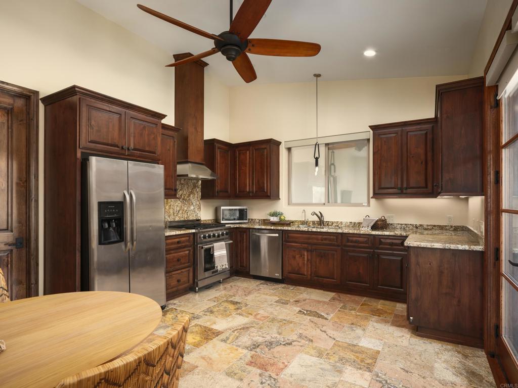 15731 Via De Santa Fe Rancho Santa Fe, CA 92067 - Photo 20 of 39 a kitchen with stainless steel appliances granite countertop a stove refrigerator and cabinets