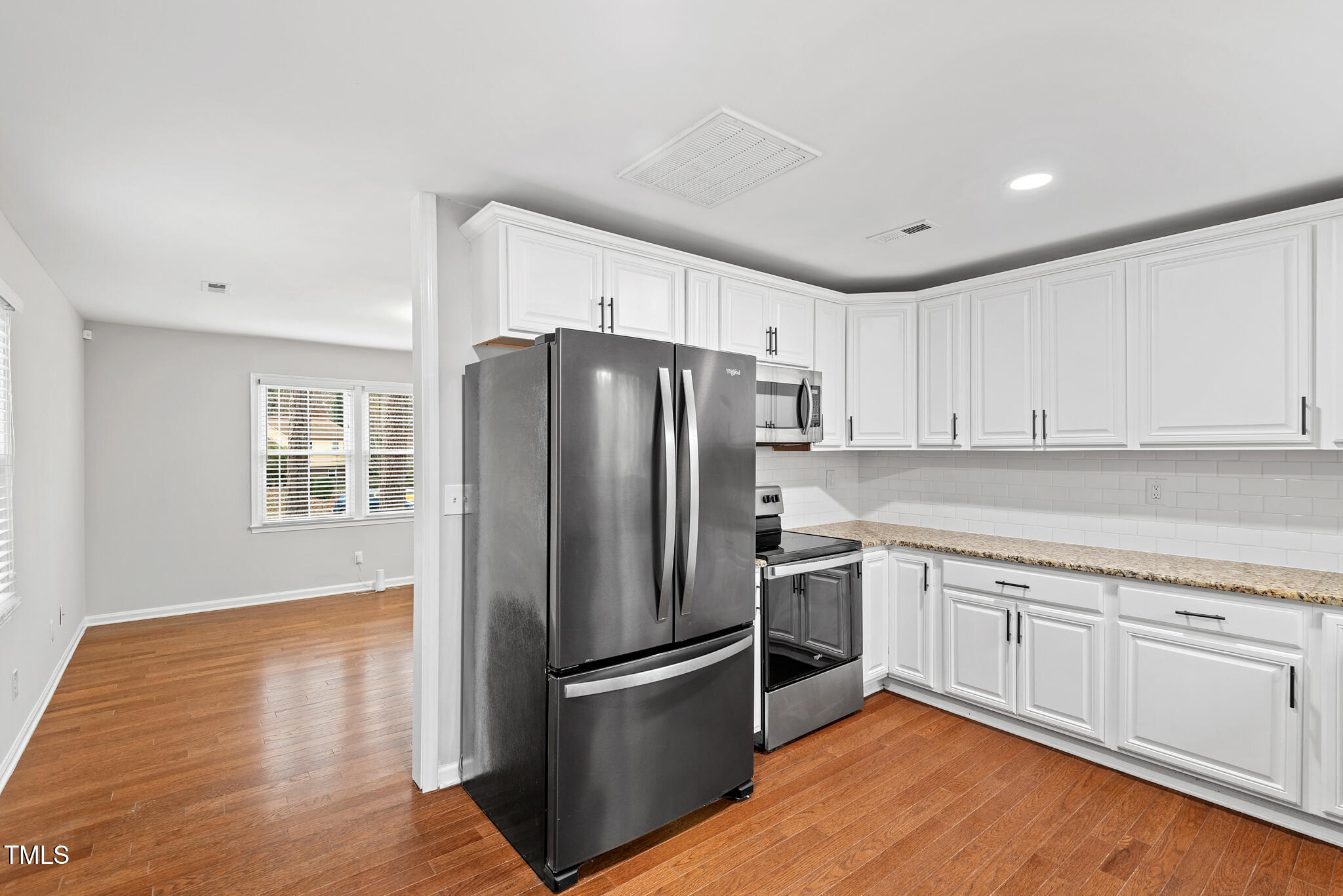 7309 Barberry Court Raleigh, NC 27615 - Photo 11 of 43 a kitchen with a refrigerator stove and white cabinets