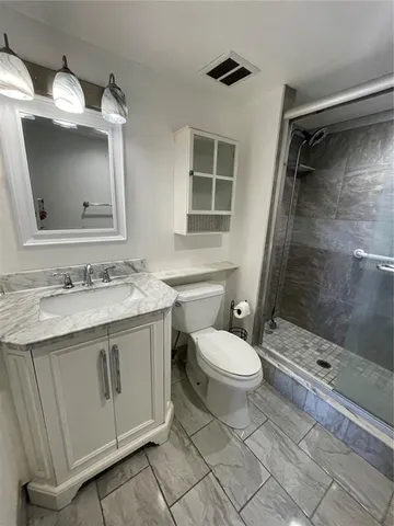 a bathroom with a granite countertop sink toilet and shower