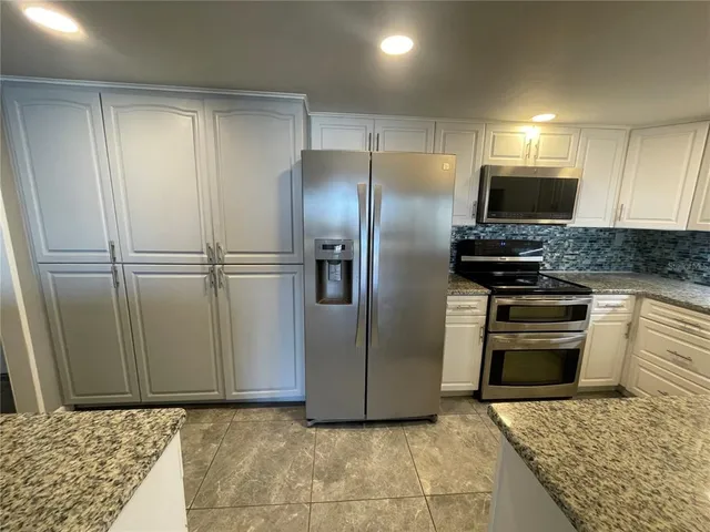 a kitchen with granite countertop a refrigerator and a stove top oven