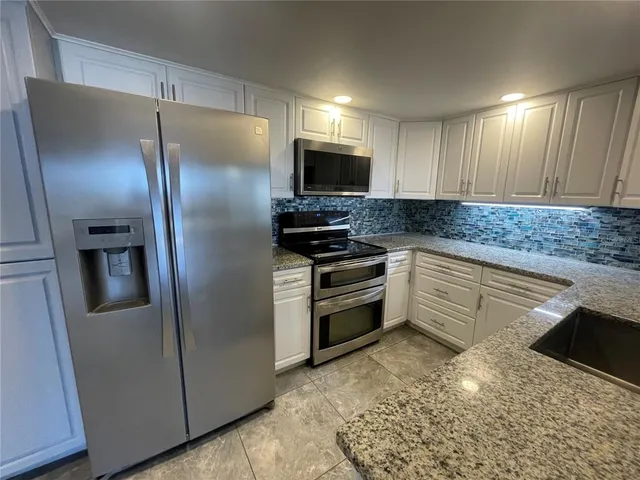 a kitchen with granite countertop a refrigerator and a sink