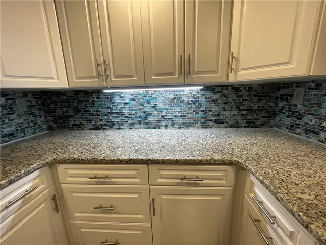 a kitchen with granite countertop white cabinets and stainless steel appliances