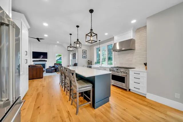 a kitchen with stainless steel appliances a dining table chairs stove and sink