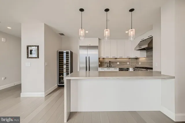 a large kitchen with stainless steel appliances kitchen island granite countertop a refrigerator a sink a stove and white cabinets