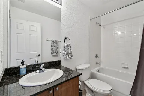 a bathroom with a granite countertop sink toilet a mirror and shower