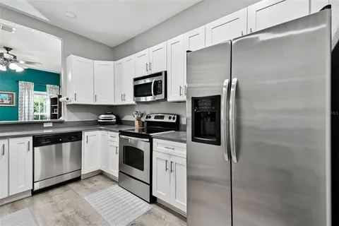 a kitchen with stainless steel appliances granite countertop a refrigerator a stove a sink and white cabinets