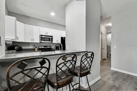 a kitchen with stainless steel appliances granite countertop a chairs a sink a stove a microwave and a refrigerator