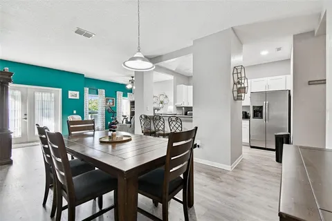 a view of a dining room and livingroom with furniture wooden floor a chandelier