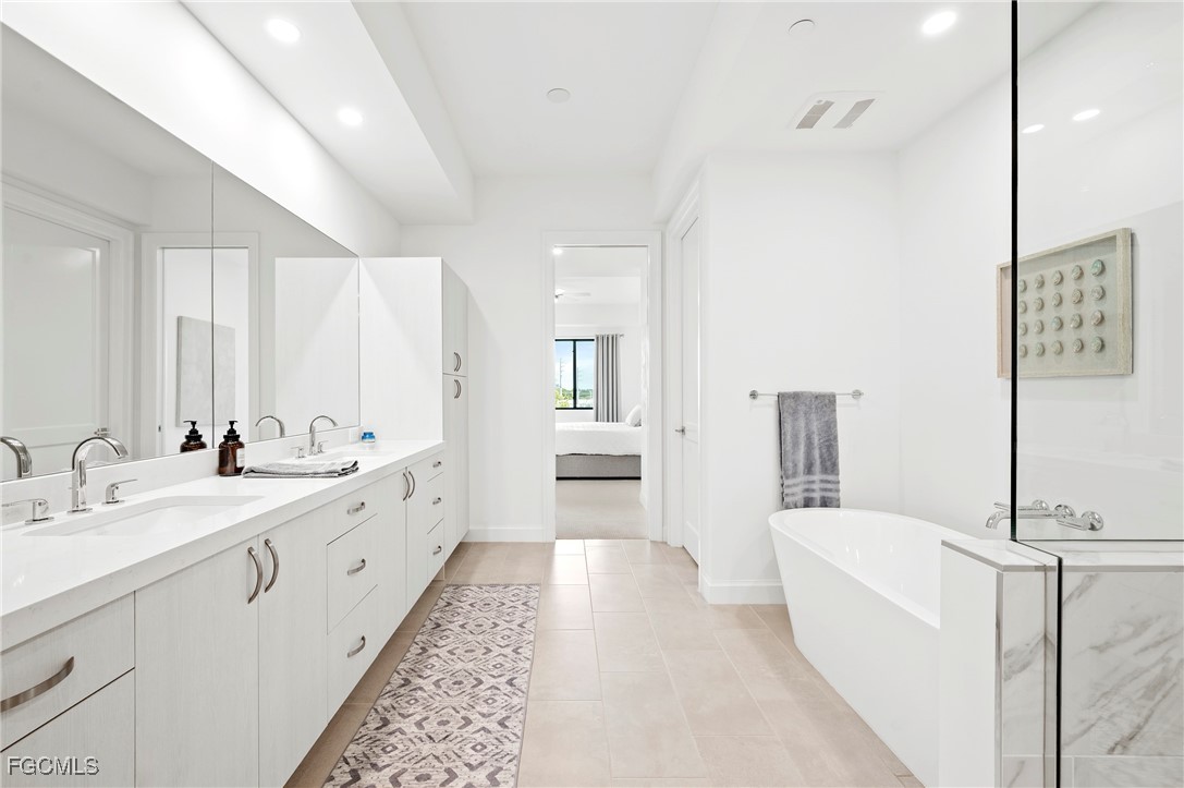 1125 Central Avenue, Unit 463 Naples, FL 34102 - Photo 21 of 42 a large bathroom with a double vanity sink a mirror and a bathtub