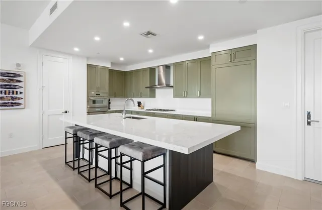 a kitchen with stainless steel appliances granite countertop a kitchen island a sink a stove and a refrigerator