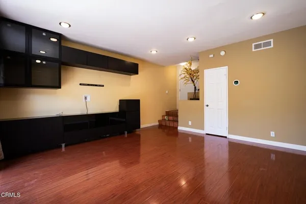 a view of empty room with wooden floor and fan