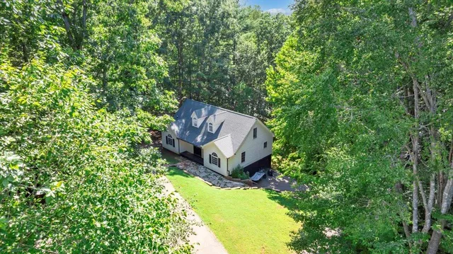 an aerial view of residential house with outdoor space and trees all around