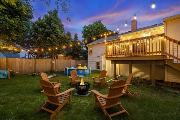 a couple of blue chairs sitting in a yard with swimming pool in the back