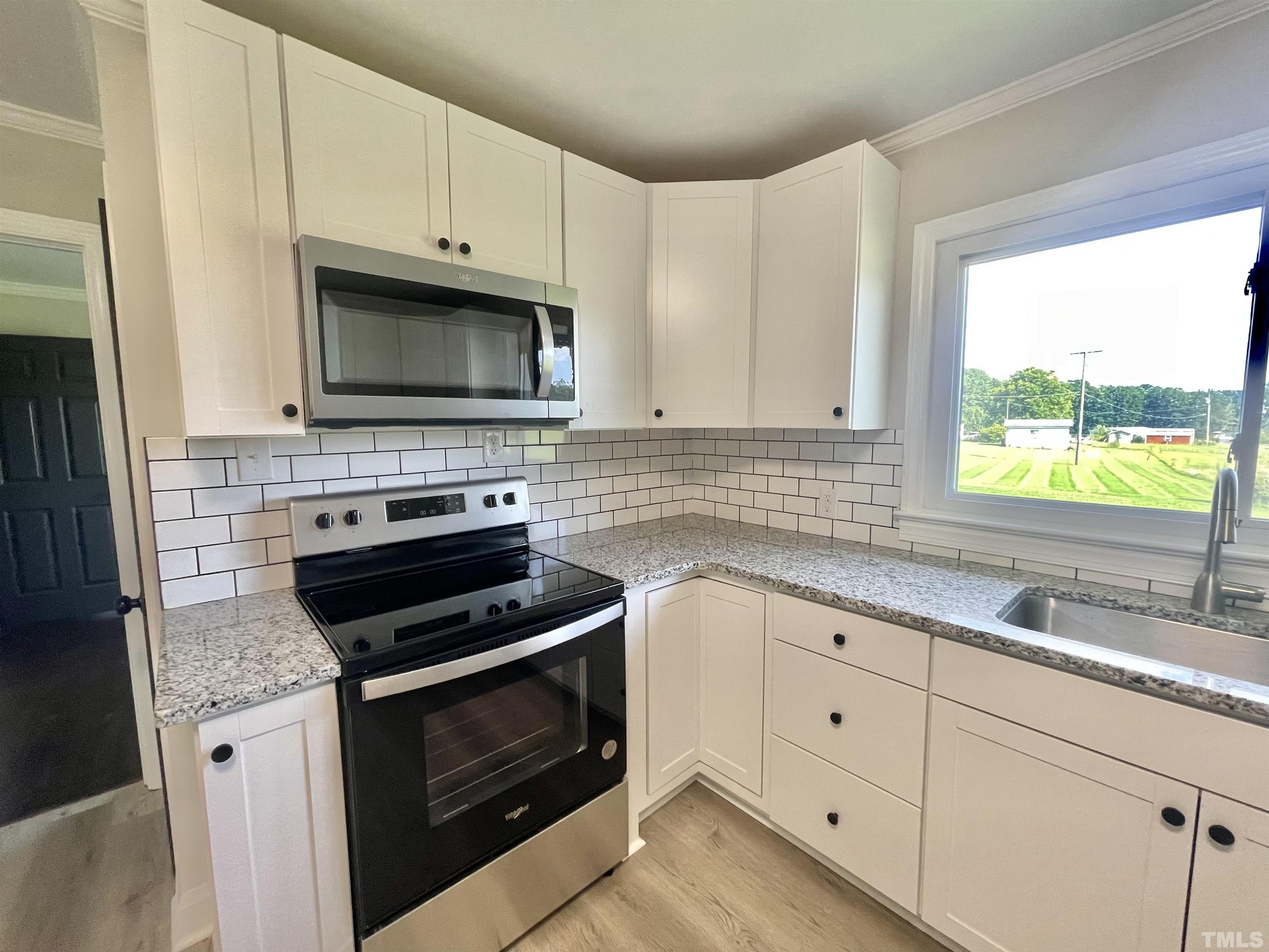 2221 Burlington Road Roxboro, NC 27574 - Photo 6 of 28 a kitchen with granite countertop white cabinets appliances and a window