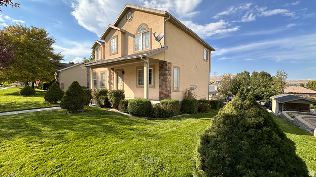 3547 East Golden Eagle Road Eagle Mountain, UT 84005 - Photo 5 of 47 View of property exterior featuring stucco siding, stone siding, a porch, and a yard