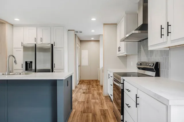 a kitchen with stainless steel appliances a sink stove refrigerator and cabinets