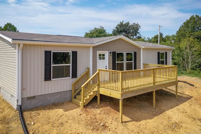 a view of a house with a wooden deck and a yard