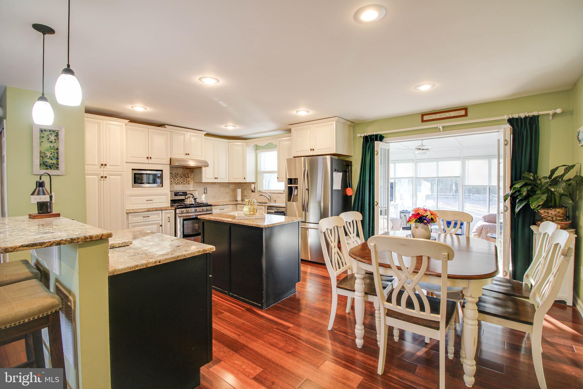 8000 Solley Road Glen Burnie, MD 21060 - Photo 7 of 44 a kitchen with stainless steel appliances kitchen island granite countertop a refrigerator a stove top oven a sink dishwasher and white cabinets with wooden floor